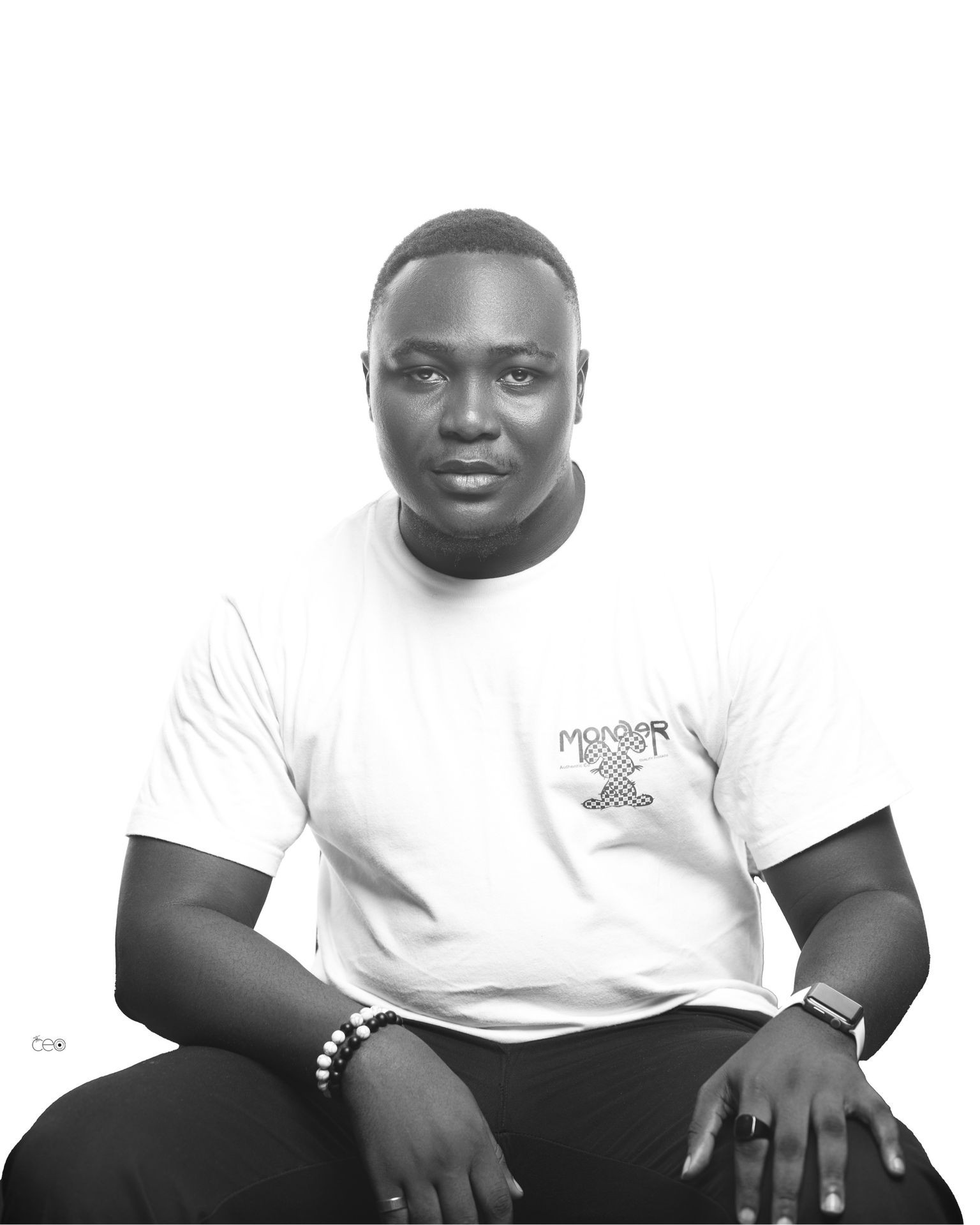 Monochrome portrait of a seated person wearing a smartwatch and beaded bracelets.